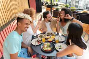 Free photo medium shot friends sitting at table