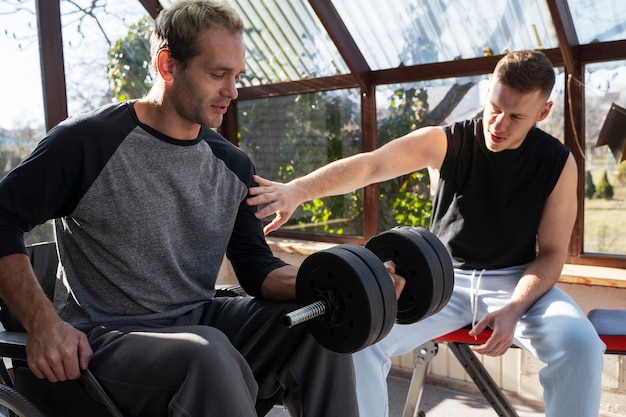 Medium shot friends training together with dumbbells