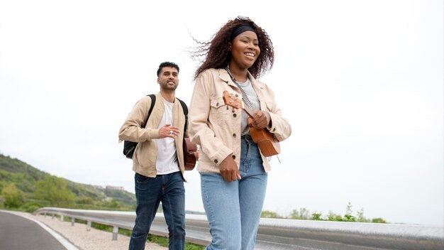 Free photo medium shot friends traveling with guitar