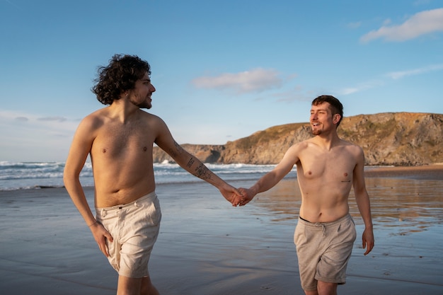 Foto gratuita coppia gay di tiro medio in spiaggia