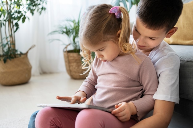 Free photo medium shot girl and boy with tablet