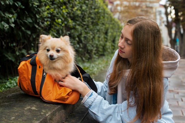 Medium shot girl carrying puppy in bag