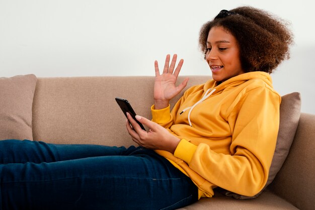 Medium shot girl on couch with phone