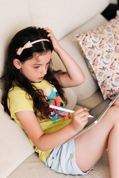 ミディアムショットの女の子がペンでタブレットに描く