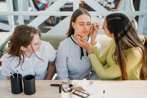 Medium shot girl getting make up from friend