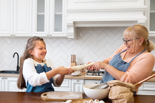 Medium shot girl and grandma holding dough