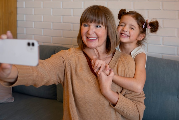 Medium shot girl and granny taking selfie