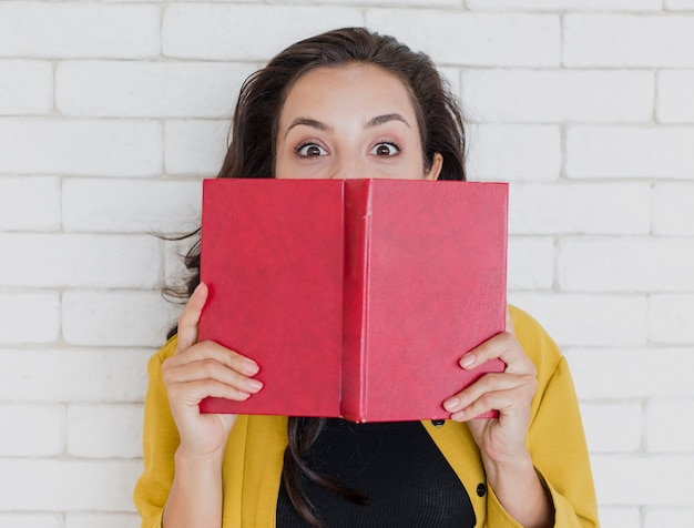 Бесплатное фото Средний снимок девушка держит книгу с красной обложкой