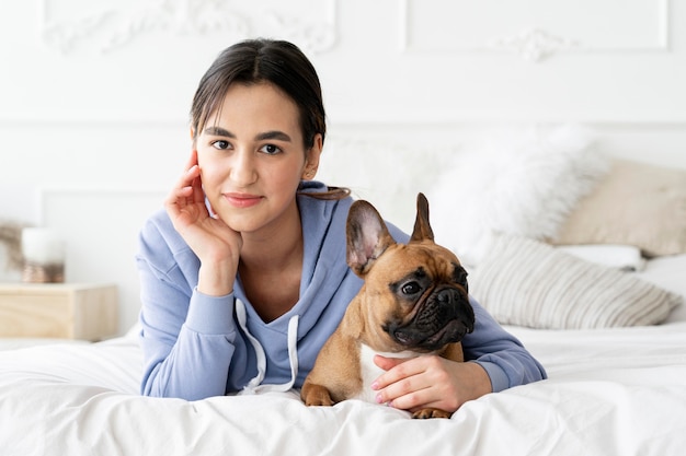 Cane della holding della ragazza del colpo medio a letto