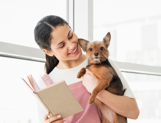 Medium shot girl holding dog and book