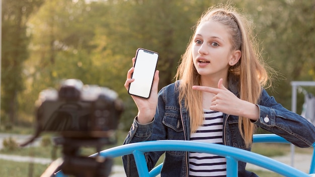 Foto gratuita smartphone della tenuta della ragazza del colpo medio