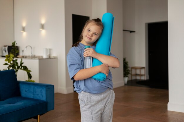 Foto gratuita stuoia di yoga della tenuta della ragazza del colpo medio