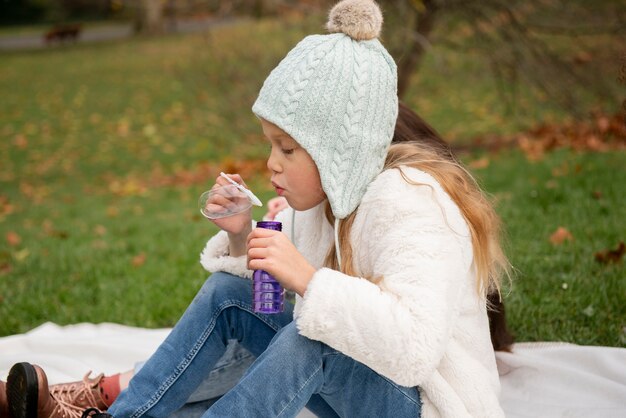 Medium shot girl making soap bubble