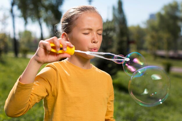 Девушка среднего кадра делает мыльные пузыри на улице