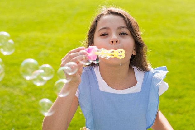 Medium shot girl making soap bubbles 