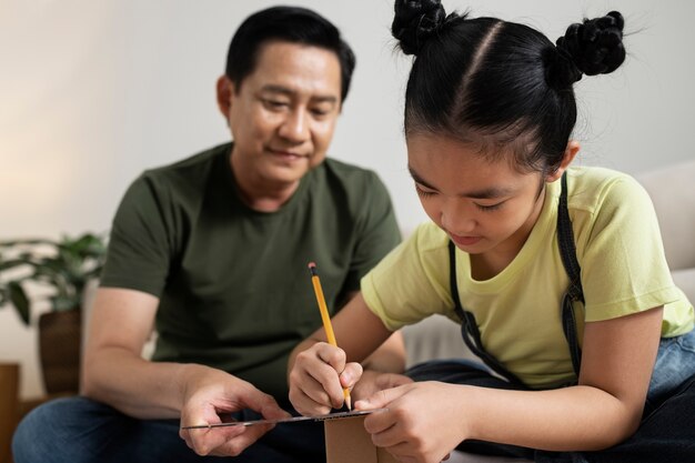 Medium shot girl and man making cardboard house