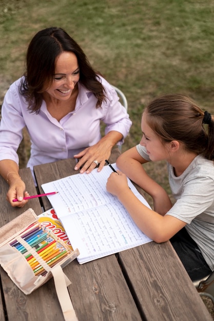 Medium shot girl and mother doing homework