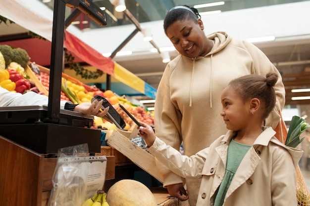 Medium shot girl paying at market