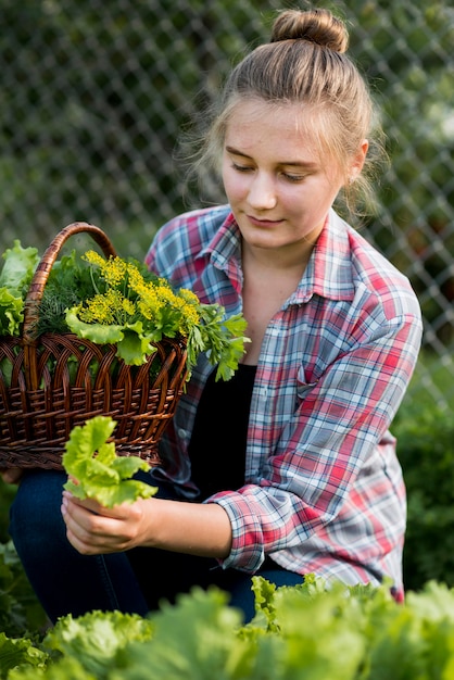 Medium shot girl picking up lettuce