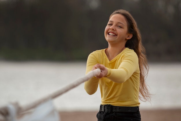 Foto gratuita ragazza del tiro medio che gioca al tiro alla fune sulla spiaggia