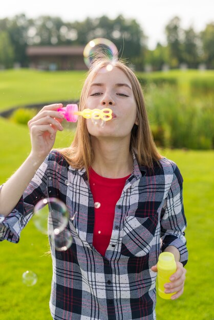 Medium shot girl playing with soap bubbles 