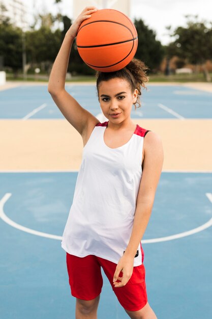 Средний снимок девушки позируют с баскетбольным мячом