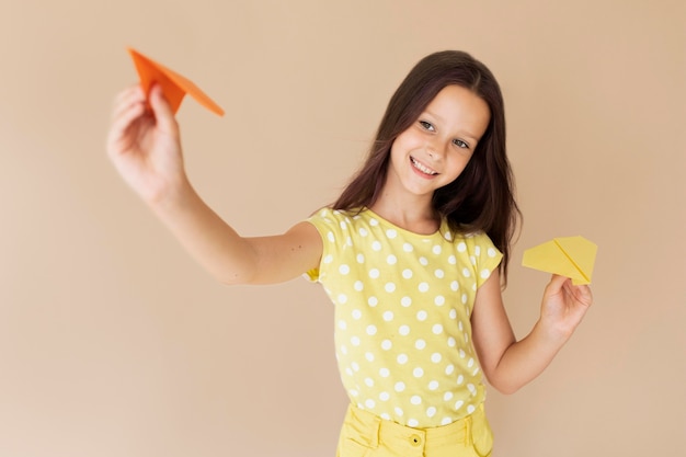 Foto gratuita ragazza di tiro medio in posa con aeroplani di carta