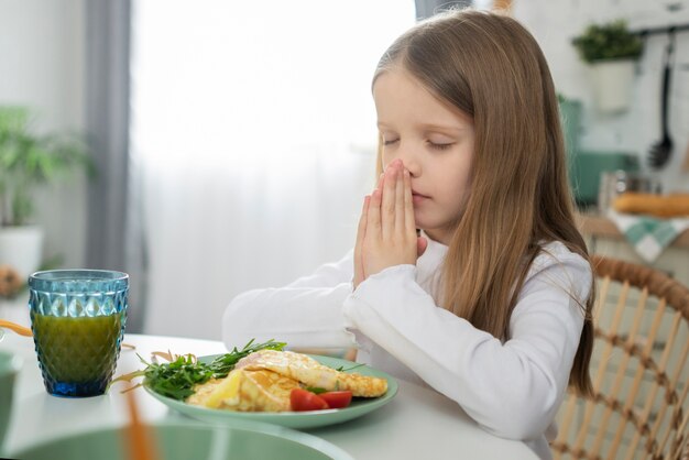 食べる前に祈るミディアムショットの女の子