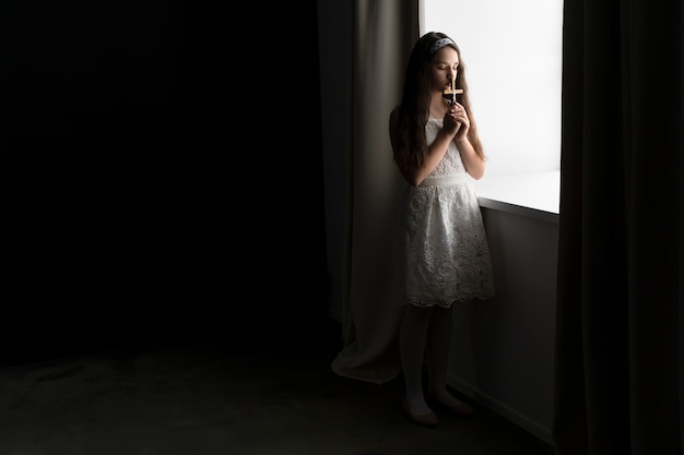 Medium shot girl praying with crucifix