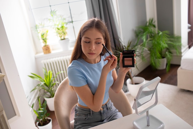 Free photo medium shot girl putting on makeup