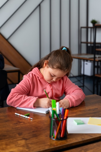 Foto gratuita ragazza di tiro medio che studia a scuola