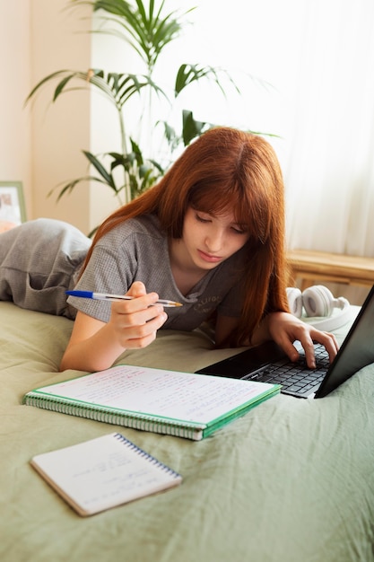 Девушка среднего кадра учится с ноутбуком