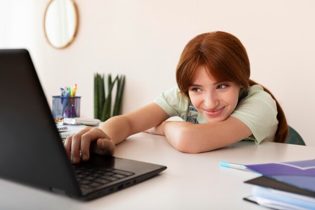 Medium shot girl studying with laptop