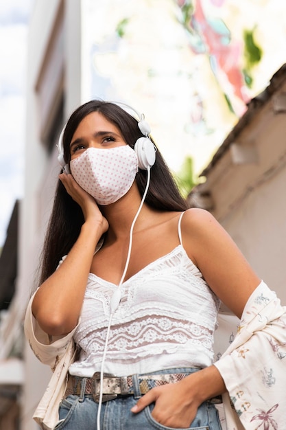 Free photo medium shot girl wearing mask and headphones