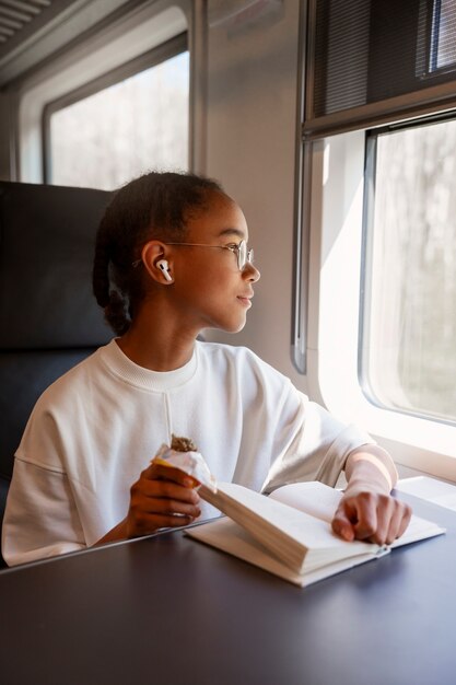 電車の中で本を持つミディアムショットの女の子