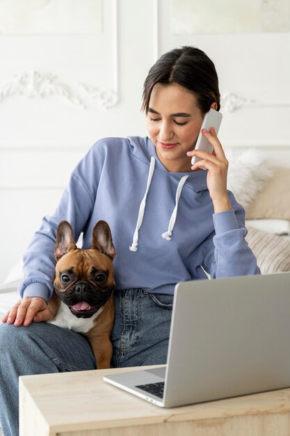 Ragazza del colpo medio con il cane che parla sul telefono