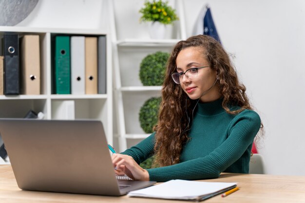 Medium shot girl with headphones studying indoors