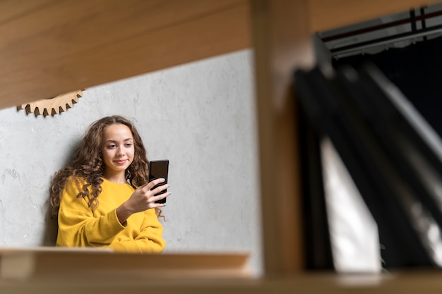 Free photo medium shot girl with smartphone indoors