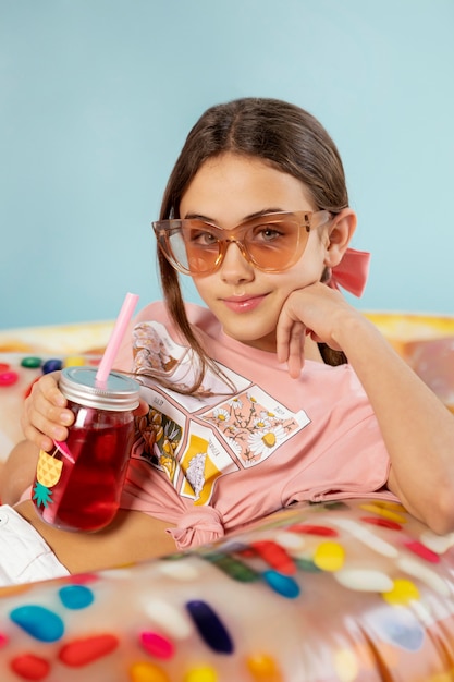 Ragazza del colpo medio con occhiali da sole e drink