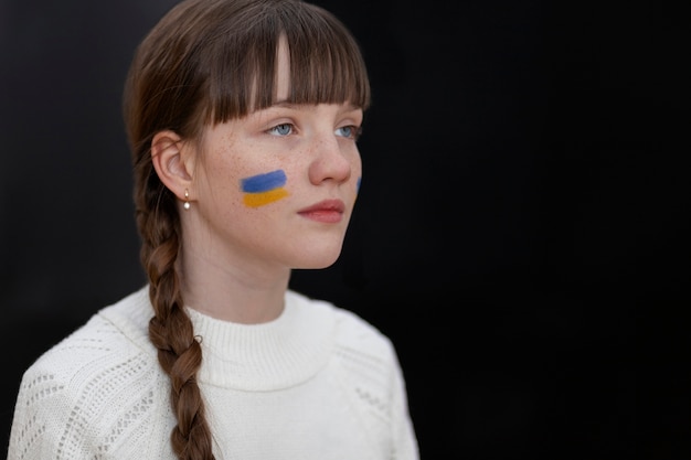 Free photo medium shot girl with ukranian flag on face