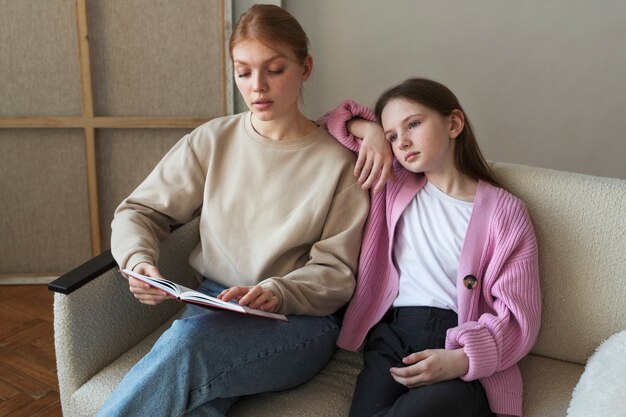 Medium shot girl and woman sitting on couch