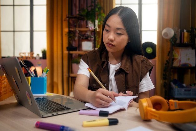 Foto gratuita ragazza del colpo medio che scrive in taccuino