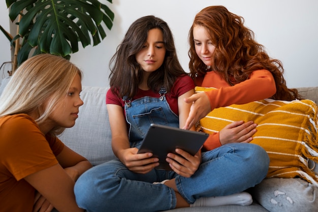 Free photo medium shot girls looking at tablet