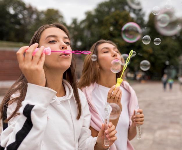 Foto gratuita ragazze di tiro medio che fanno palloncini di sapone