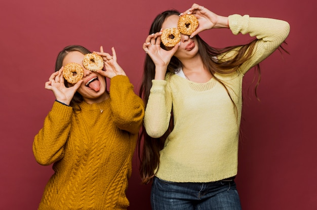 Free photo medium shot girls with doughnuts making faces