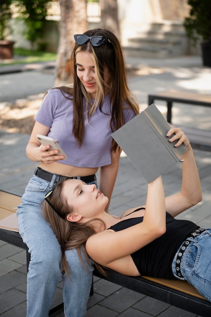 Medium shot girls with smartphone and book