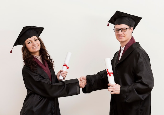 Medium shot graduates shaking hands