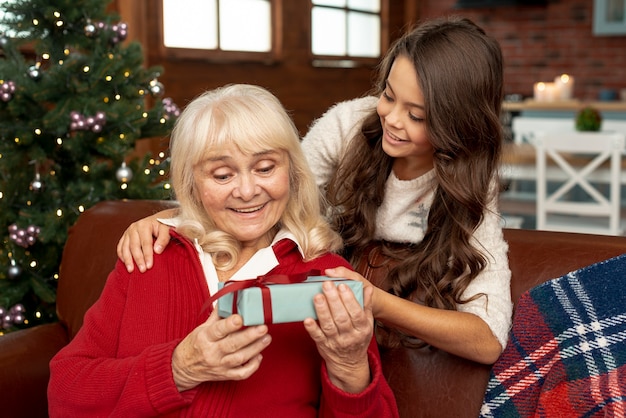 Medium shot granddaughter offering grandma a gift
