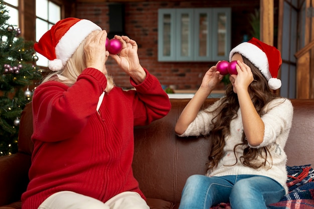 Бесплатное фото Средний выстрел бабушка и ребенок, играющий с рождественскими шарами