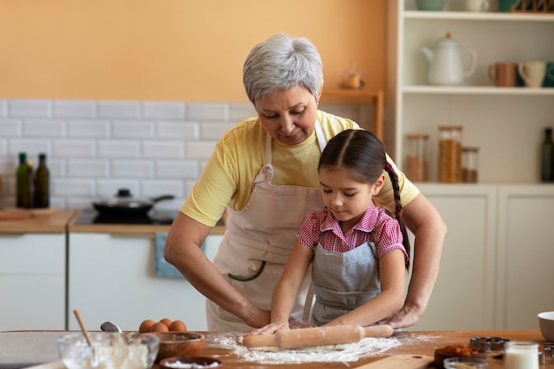 Free photo medium shot grandma and girl cooking together